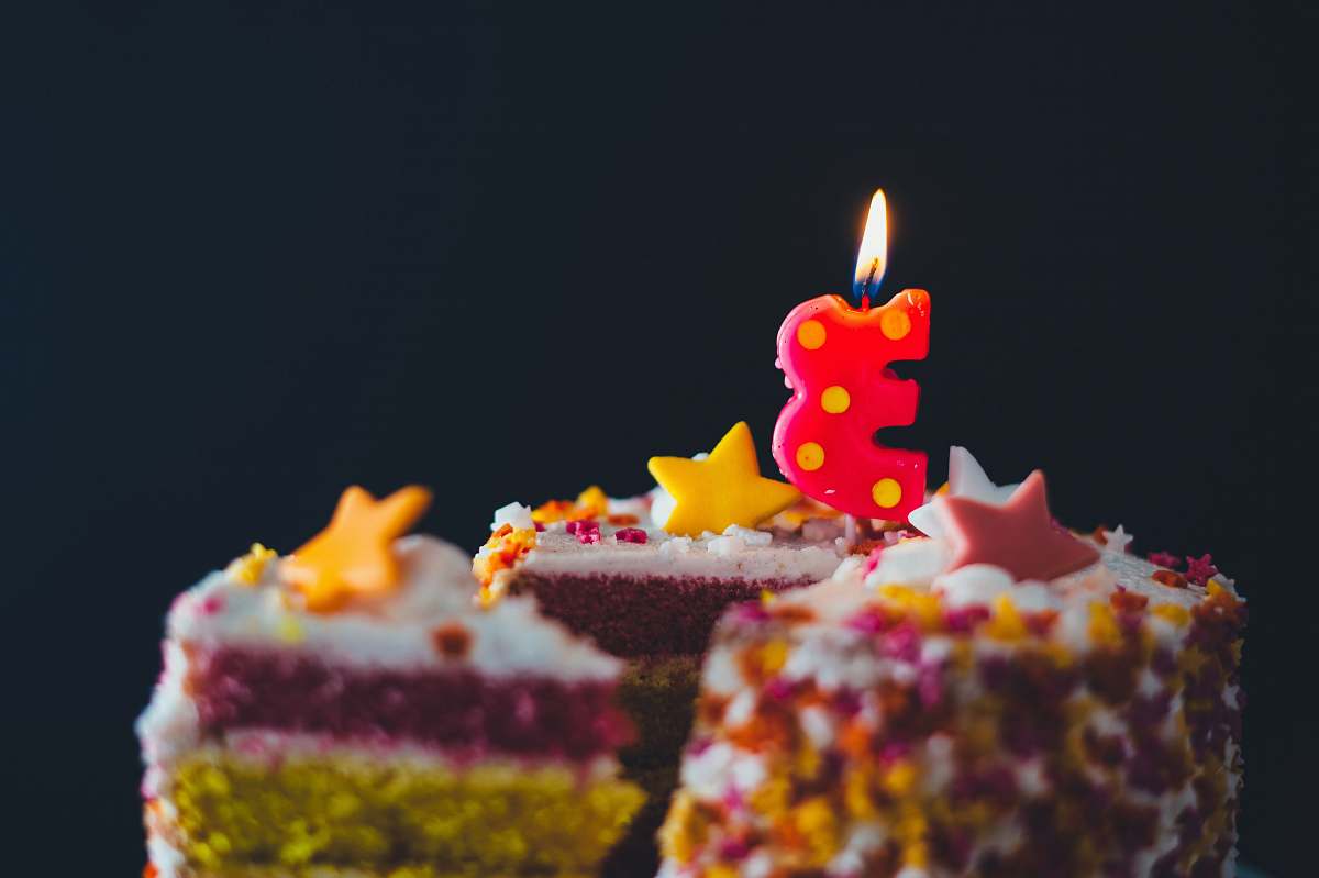 birthday cake multicolored icing covered cake with 3 cut-out candle candle